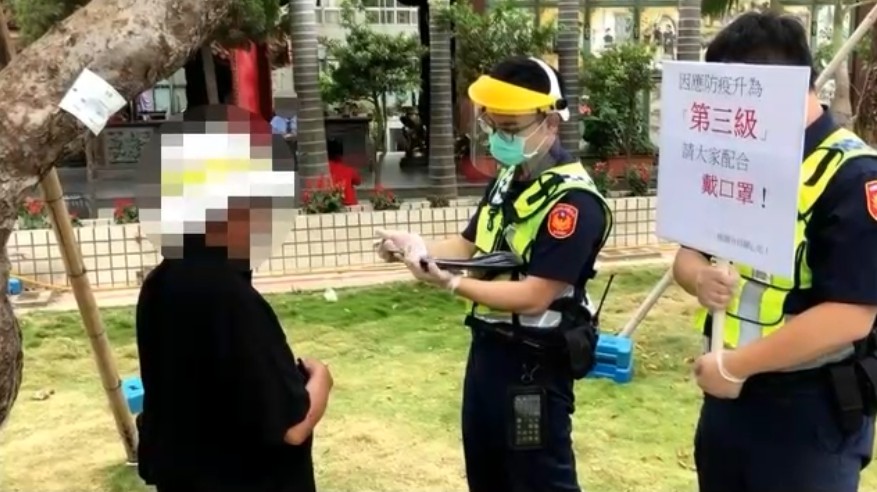桃園景福派出所員警發現坐於草地上男子未依規定戴口罩，立即上前盤查並開單移請相關單位裁處。 圖：桃園分局／提供