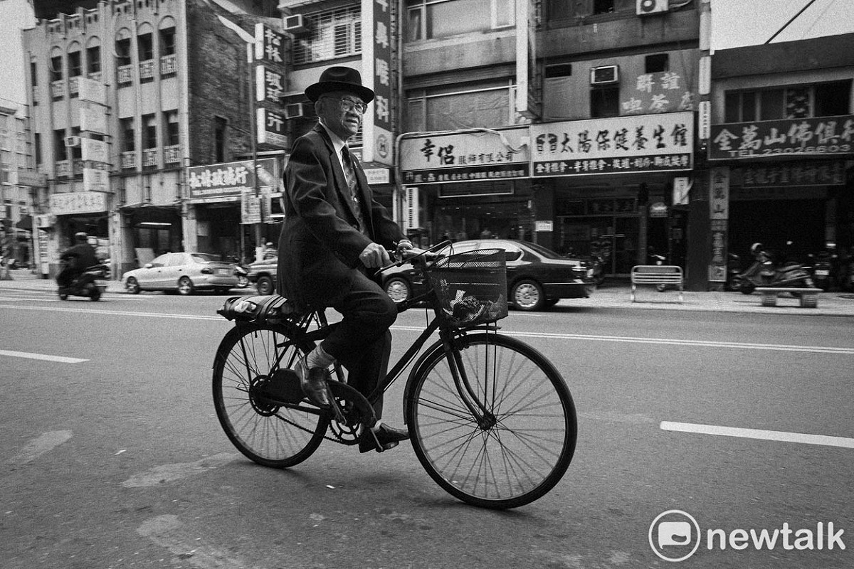 一位穿西裝的老爺爺騎著腳踏車經過龍山寺旁的西園路。照片攝於2014年。 圖：張良一/攝