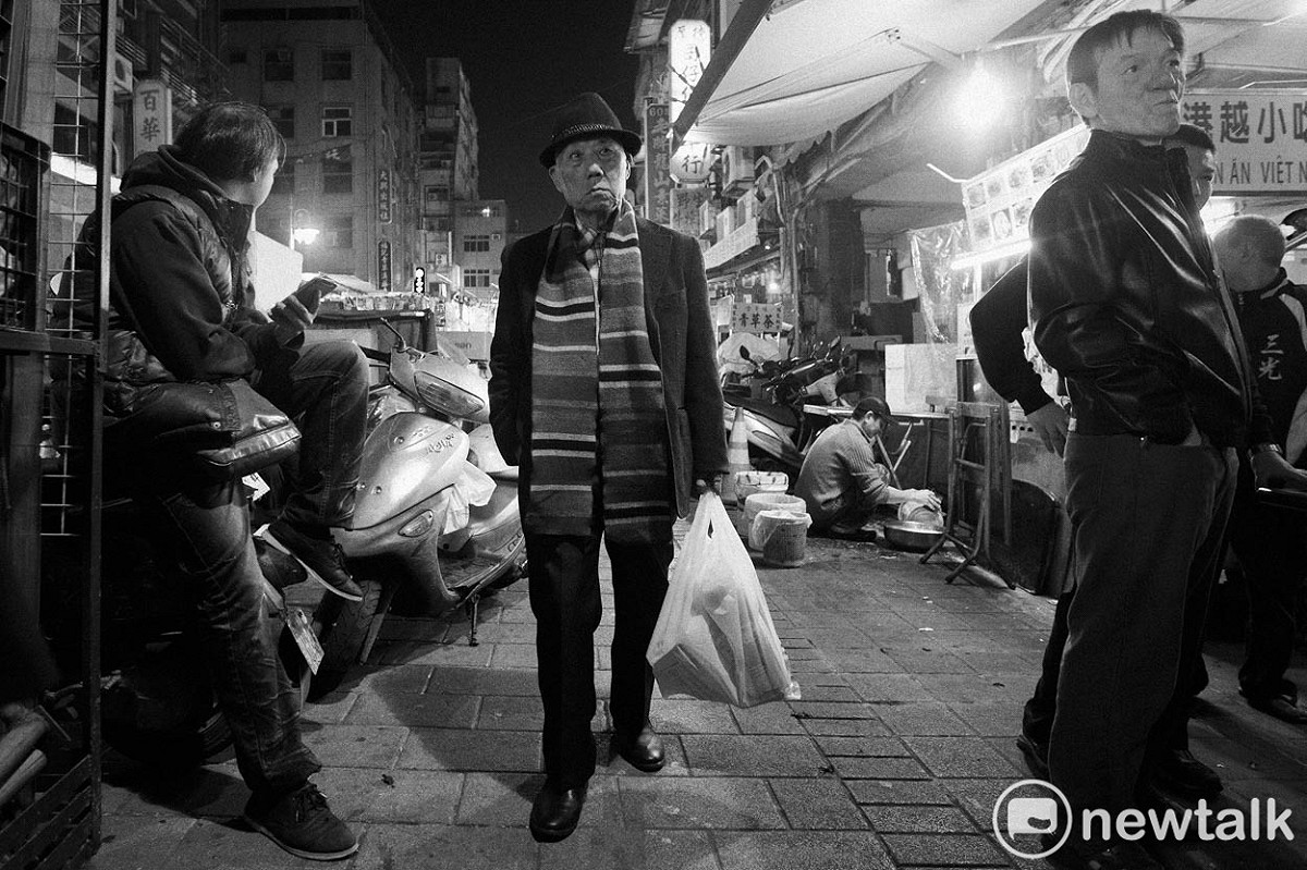 一位提著塑膠袋的民眾走在萬華西昌街夜市。照片攝於2016年，萬華西昌街。 圖：張良一/攝
