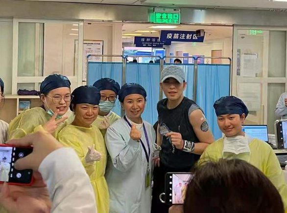 蕭敬騰接種完後，還脫下口罩案醫護人員開心合照。 圖：翻攝自微博