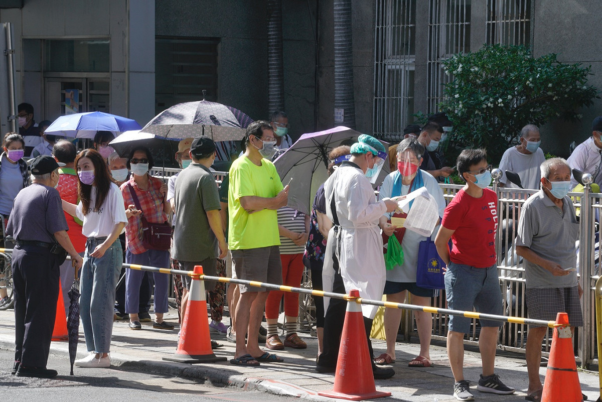 許多長者頂著大太陽擠在仁濟醫院外排隊領號碼牌。 圖：張良一 / 攝