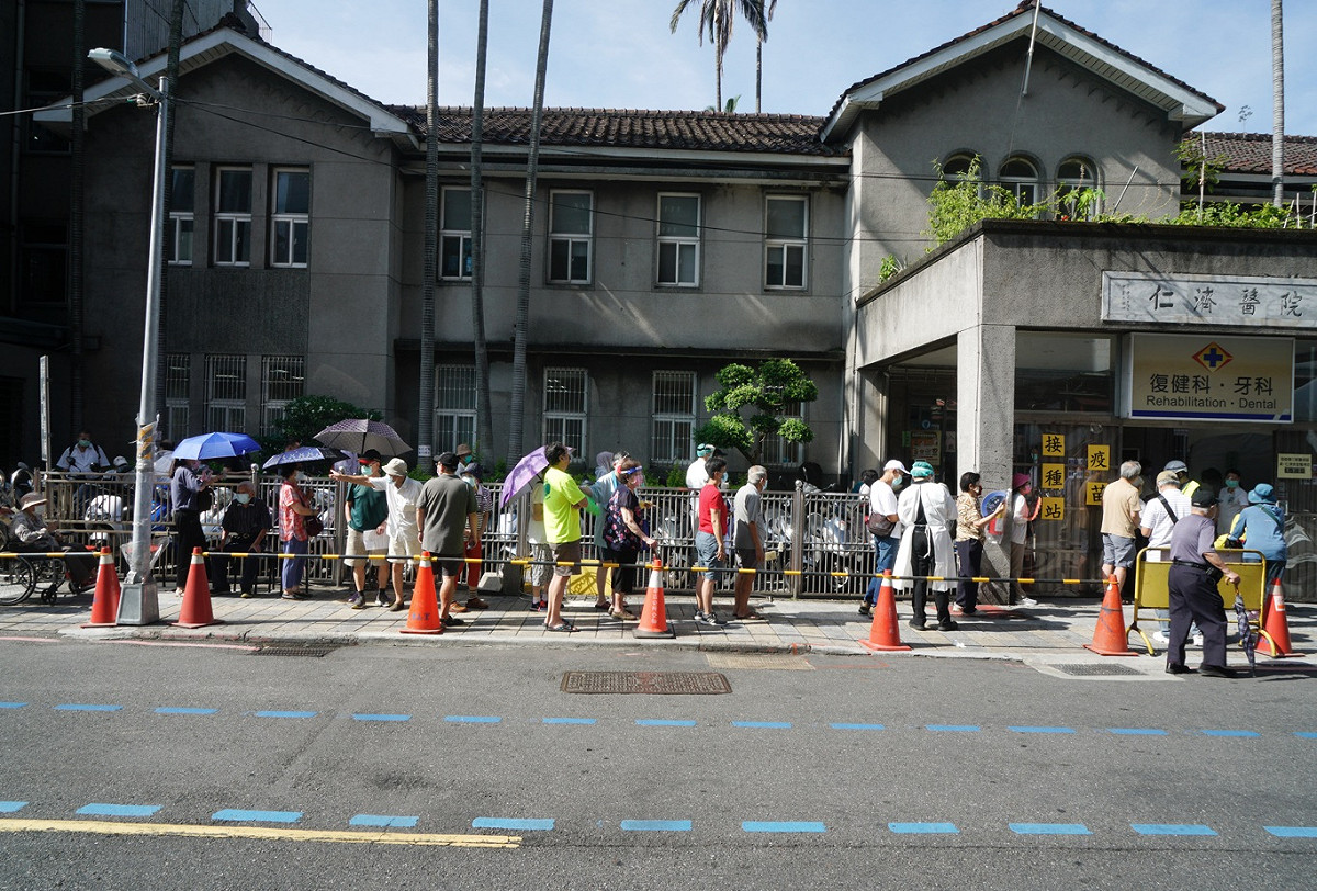 大批長者在萬華仁濟醫院外頂著大熱天排隊領號碼牌，完全無法拉出社交距離。 圖：張良一/攝