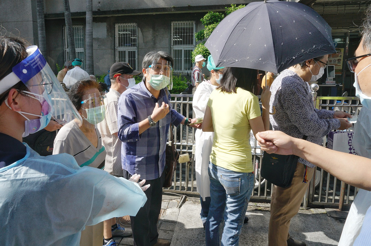 一位民眾不滿已經先在網路預約接種疫苗，卻還要在醫院外排隊領號碼牌。 圖：張良一/攝