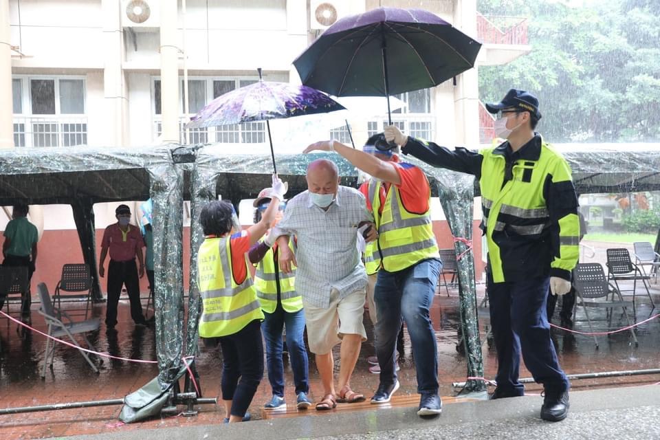 員警幫施打疫苗的長輩打傘。 圖：高雄市政府/提供