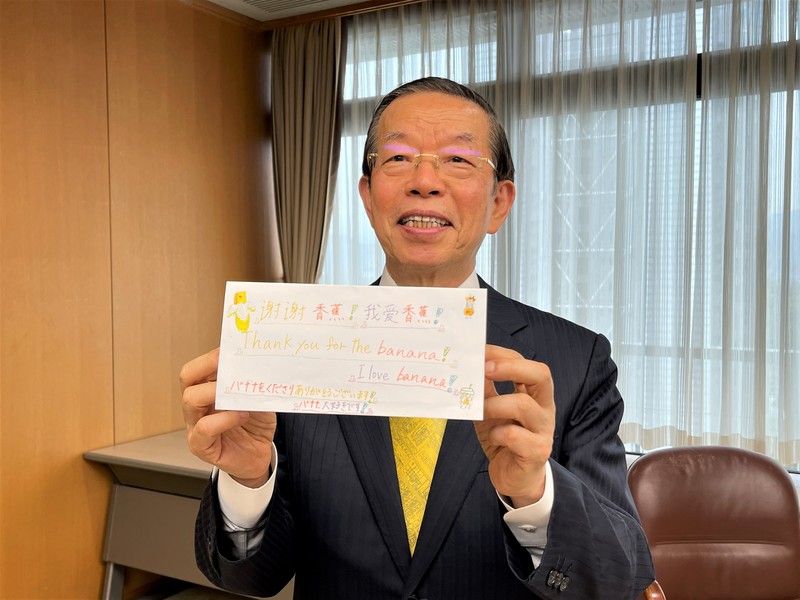 有國人指台灣是「疫苗乞丐」，駐日代表謝長廷表示，日、美在捐疫苗時都特別言及曾獲台灣馳援，日美並無施捨或傲慢的心理。圖為謝長廷23日贈台灣香蕉給靜岡市小學童，獲致謝卡。 圖：中央社提供