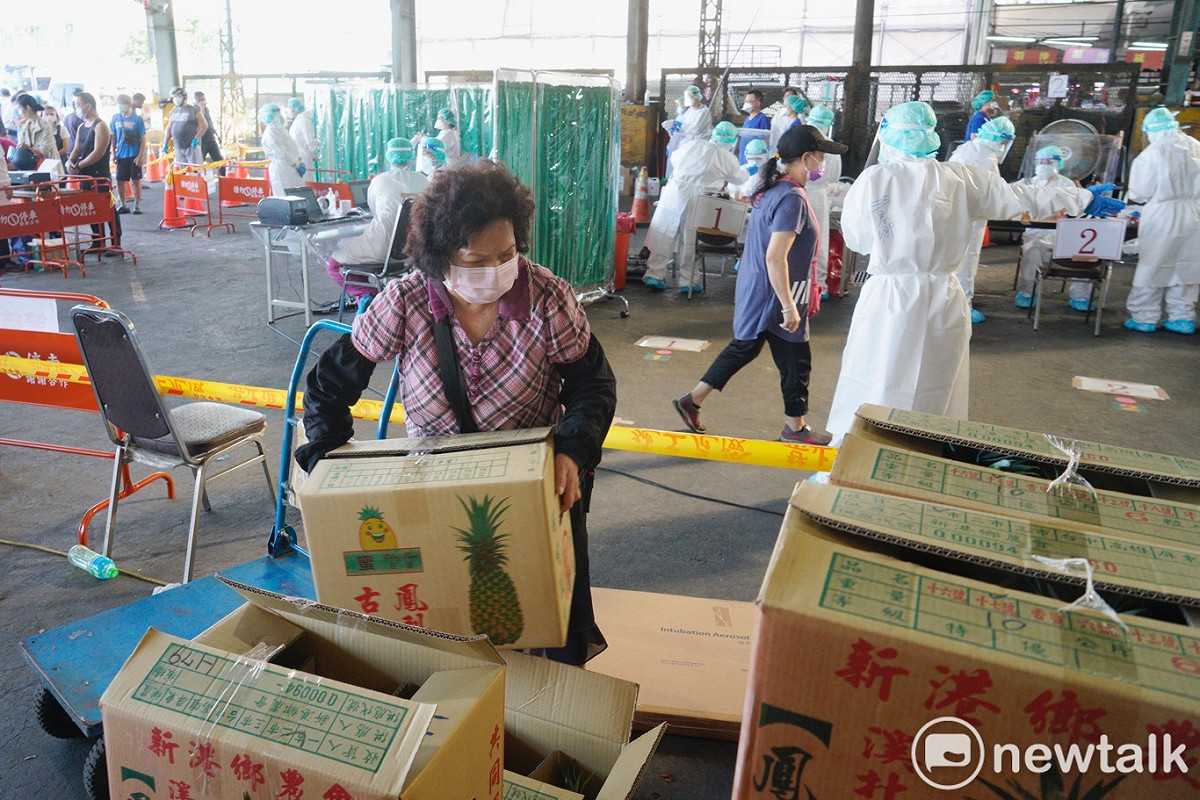 北農一市的工作人員在蔬果拍賣結束後，忙著將蔬果運出拍賣場，支援北農一市快篩的榮總醫護人員也同時在場內為工作人員進行快篩。 圖：張良一/攝