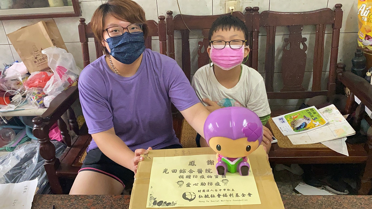 受疫情影響生活的嘉軒(右)與姐姐收下關懷物資，欣慰表示能減輕經濟負擔。 光田綜合醫院/提供
