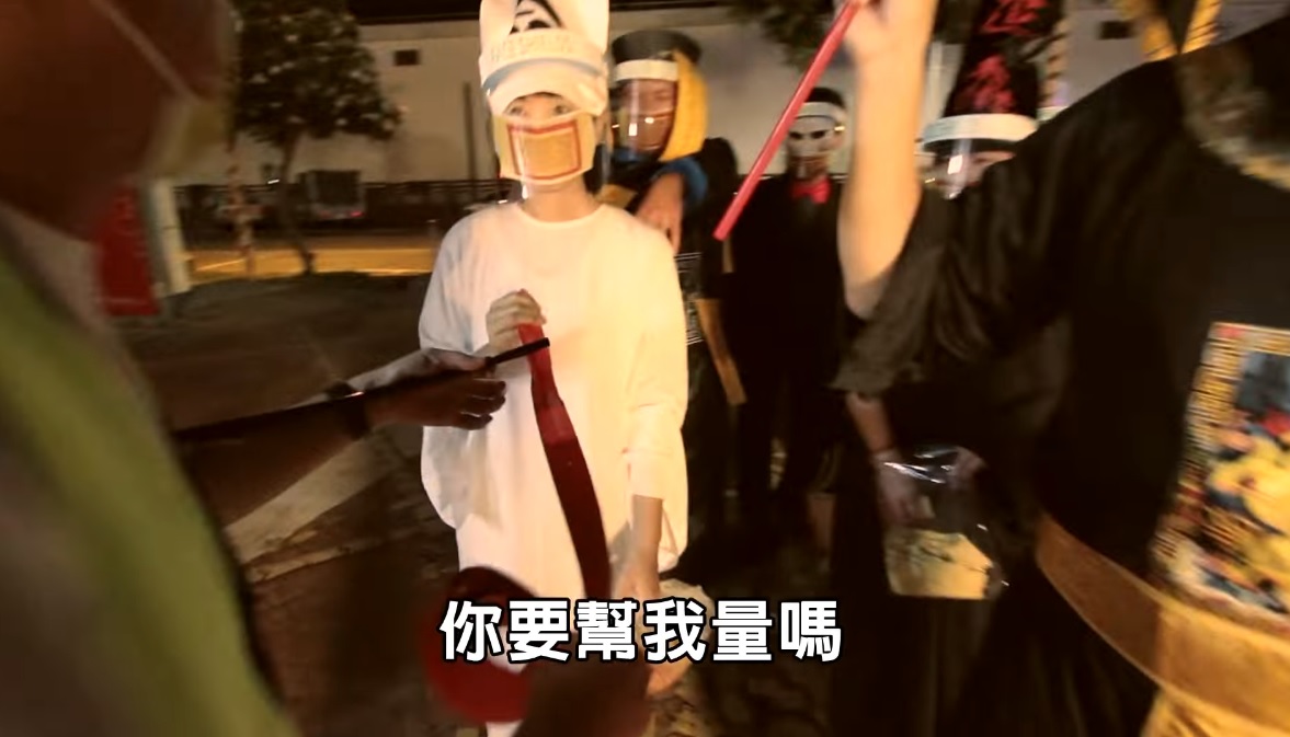 虎尾鎮公所拍攝搞笑防疫鬼片，片中白無常（中）的長舌頭直接被拔下來量社交安全距離，笑翻網友。 圖：翻攝自虎尾鎮公所臉書影片