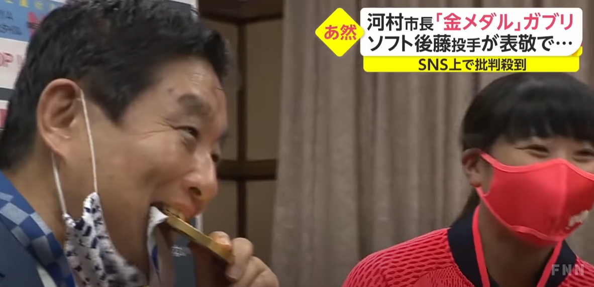 日本愛知縣名古屋市長河村隆在眾目睽睽下拉下口罩大口咬了後藤的金牌，挨批太過失禮。 圖：翻攝富士新聞網Youtube頻道
