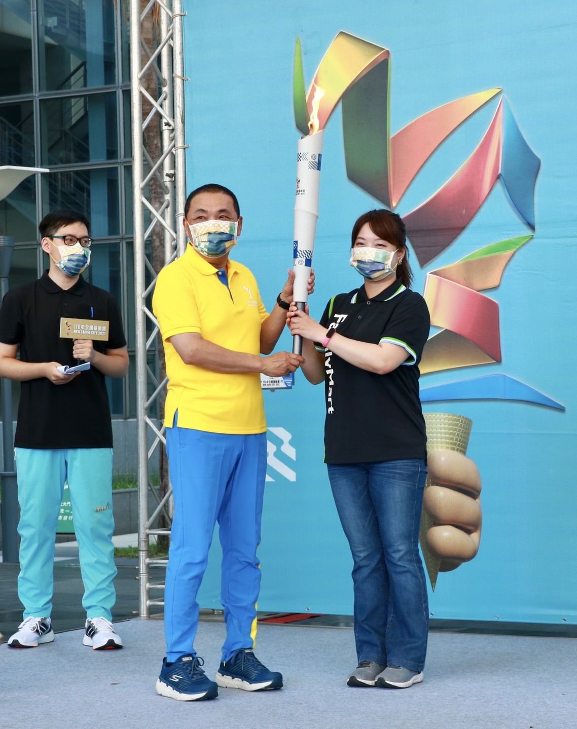 侯友宜將火炬交給網路聖火濾鏡的合作夥伴全家便利商店代表。 圖：新北市體育處提供