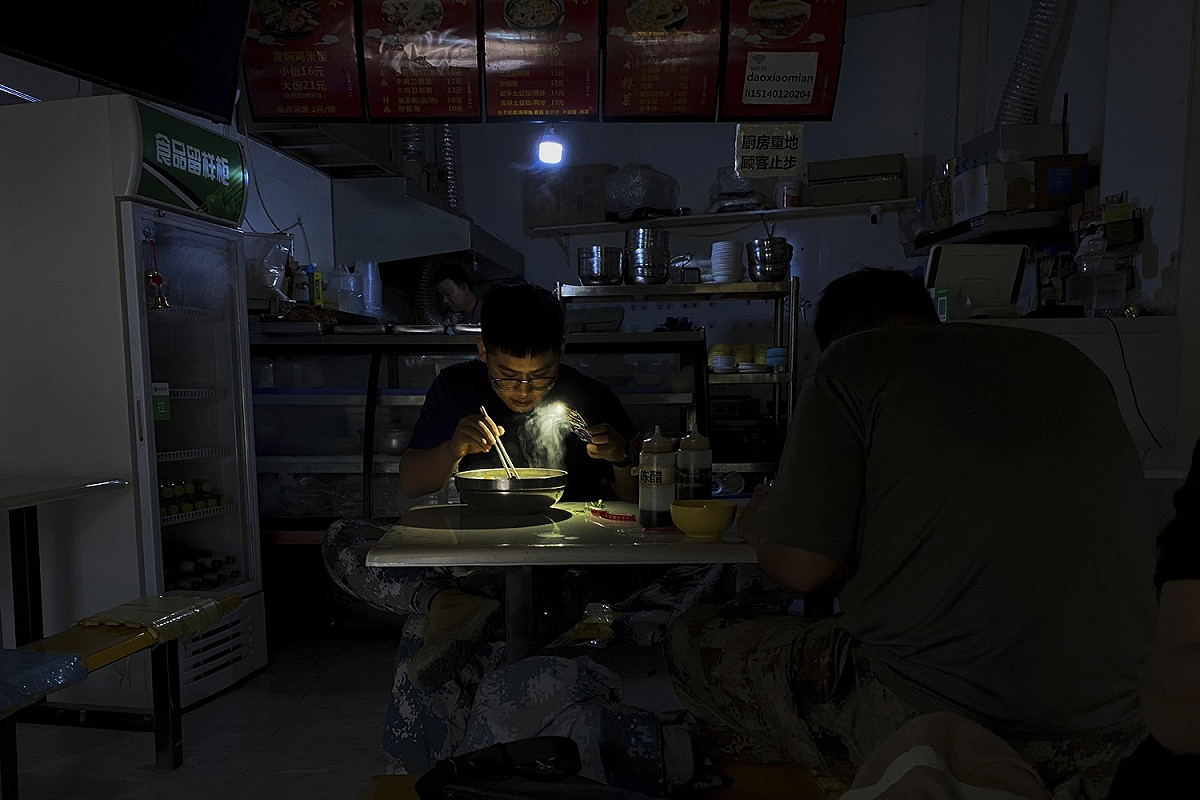 中國東北地區顧客摸黑用餐，只好利用手機的手電筒功能看清碗內食物 圖:達志影像/美聯社