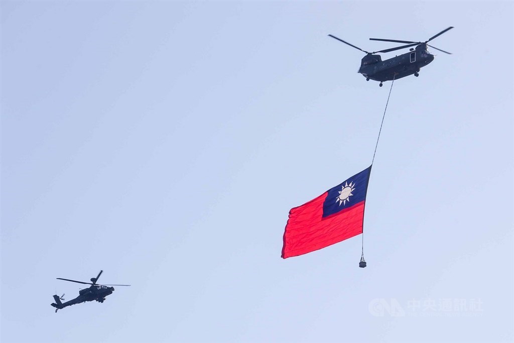 國軍30日舉行空中全兵力預演，空軍CH-47運輸直升機吊掛巨幅國旗，在AH-64E阿帕契直升機伴飛下通過台北上空。 圖：中央社