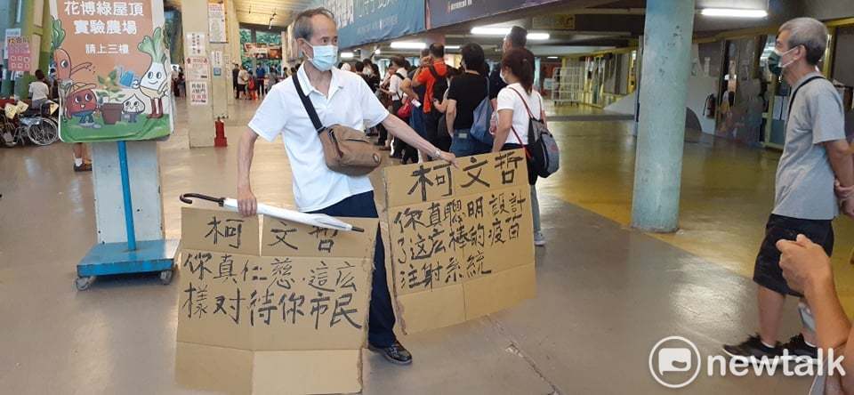 有阿伯打不到疫苗氣炸，用紙箱寫上抗議標語，怒嗆「柯文哲，你真仁慈，這樣對待你市民，柯文哲，你真聰明，設計這麼棒的疫苗注射系統！」 圖／讀者提供
