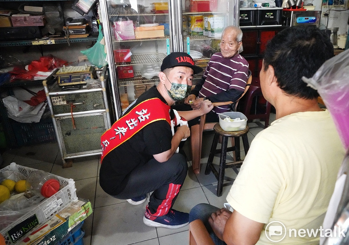 陳柏惟在大肚市場拜票時，忍著腳傷蹲下來向一位阿公致意。 圖：張良一/攝（資料照片）