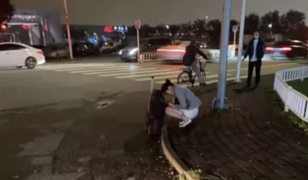 海航空姐著夏服蹲在路邊等車凍得瑟瑟發抖。 圖：翻攝 微博