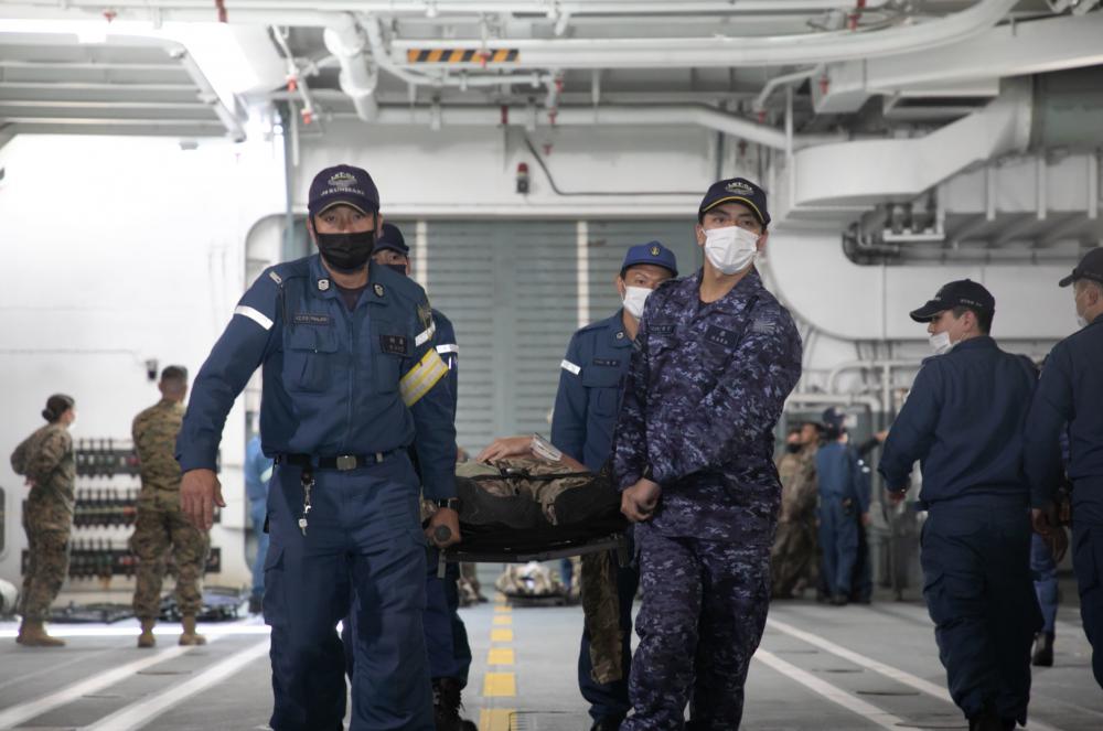美日聯合偏遠島嶼災難演習，日本海上自衛隊以擔架將傷患抬進臨時充當醫療船的「大隅級」兩棲船塢運輸艦「國東號(LST-4003)」。 圖：翻攝III MEF Marines推特