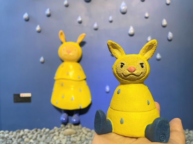 陳韋竹創作「雨天」裡穿著黃色雨衣的兔子，以純手工捏塑、彩繪的迷你版公仔，療癒性十足。 圖：鶯歌陶瓷博物館提供