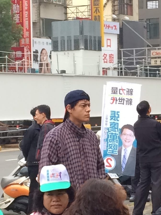 長得極像蔣友青的男子，反戴球帽，在綠營的造勢場子聽了將近1個半小時的演講。 圖：林姓民眾提供