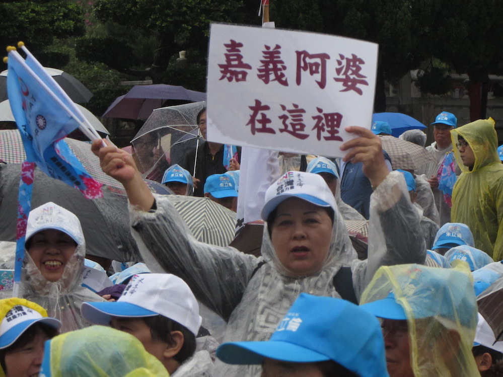 朱立倫、王如玄全國客家後援會團結大會3日舉行，儘管雨勢很大，來自各地的支持者熱情不減，更準備「阿婆在這裡」的標語。 圖：邱珮文/攝