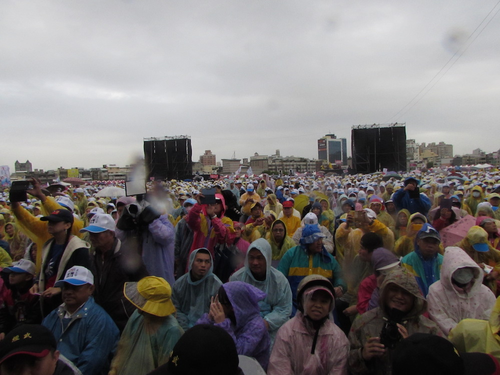 廟會嘉年華活動在綿綿陰雨中舉行，近萬民眾身穿雨衣、手拿朱立倫的競選旗幟相挺。 圖：邱珮文/攝