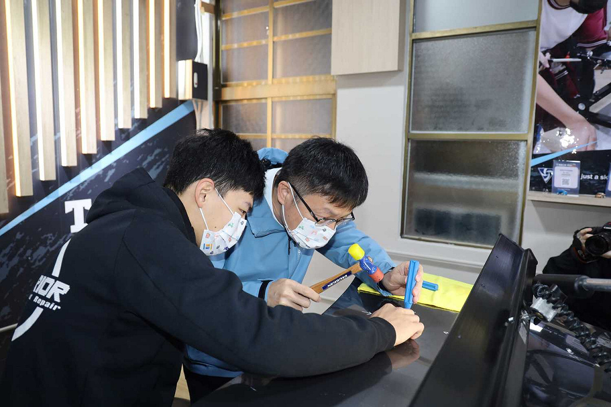 教育局長張明文(右)與南強汽修科學生體驗車門微板金修護。 圖：新北市教育局提供