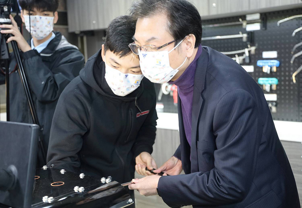 國手顏翔昱(中)向新北副巿長劉和然介紹體驗微板金教具版及工具。 圖：新北市教育局提供