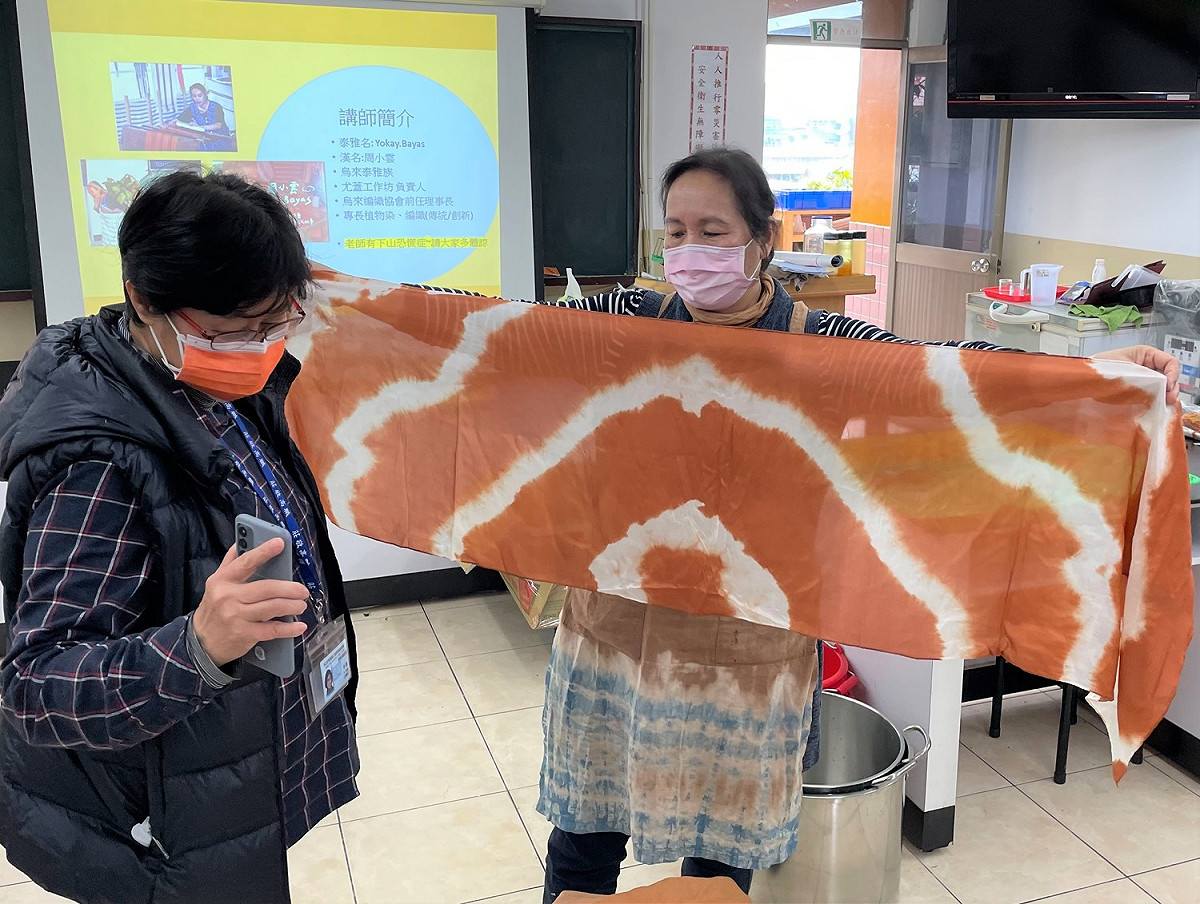 泰雅族織女老師周小雲(右一)應邀前來傳授技藝，完成植染作品後，莊敬高職老師余姮(左一)馬上開心拍照紀錄。 圖：新北市原民局提供