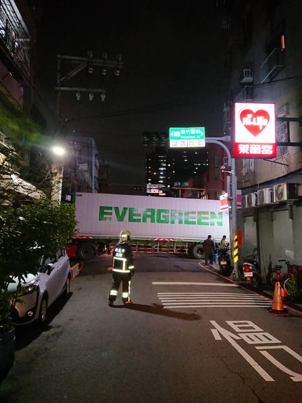 一輛長榮貨櫃車17日晚間駛入新北市三重區一處巷弄間，疑未注意電線桿高度，勾到電線桿上電線而卡住，進退不得。 圖：中央社提供