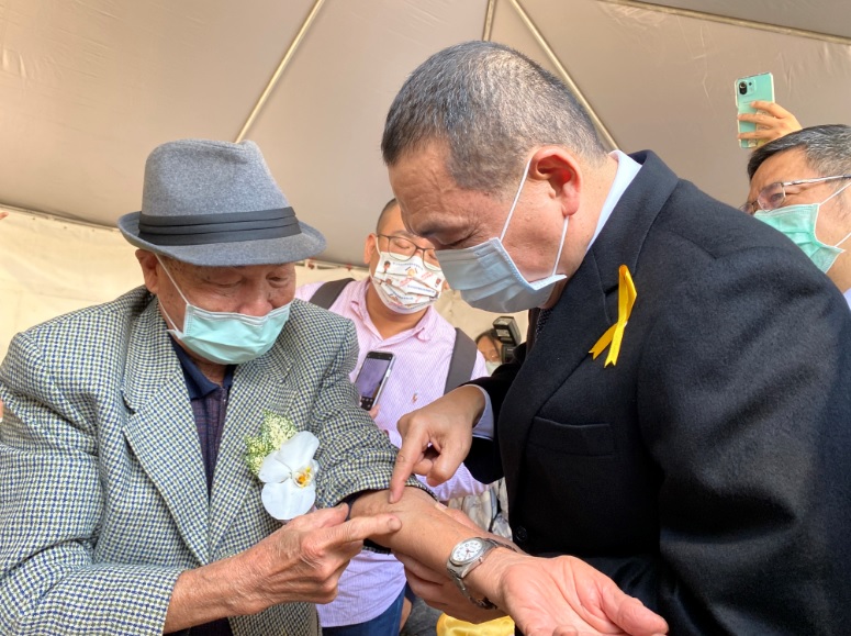 91歲趙水濱於民國36年二二八事件期間，遭軍隊圍補槍擊手臂受重傷，幾成殘廢，時年僅15歲，後只能打零工維生。侯友宜關心其傷痕。 圖：新北市民政局提供
