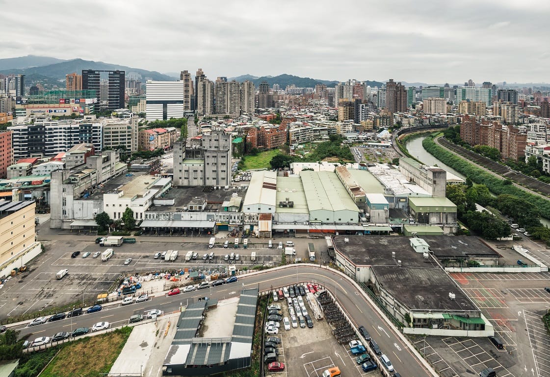 新店榮工單元2位於新店區東北隅，北側以景美溪為界與台北市文山區相鄰，計畫區內現況主要為正大尼龍工業之倉儲及辦公使用，而西側多為老舊低矮住宅，東側主要為停車場使用，南側為裕隆、宏達電等企業總部及大型賣場如家樂福等。 圖：新北市城鄉局提供