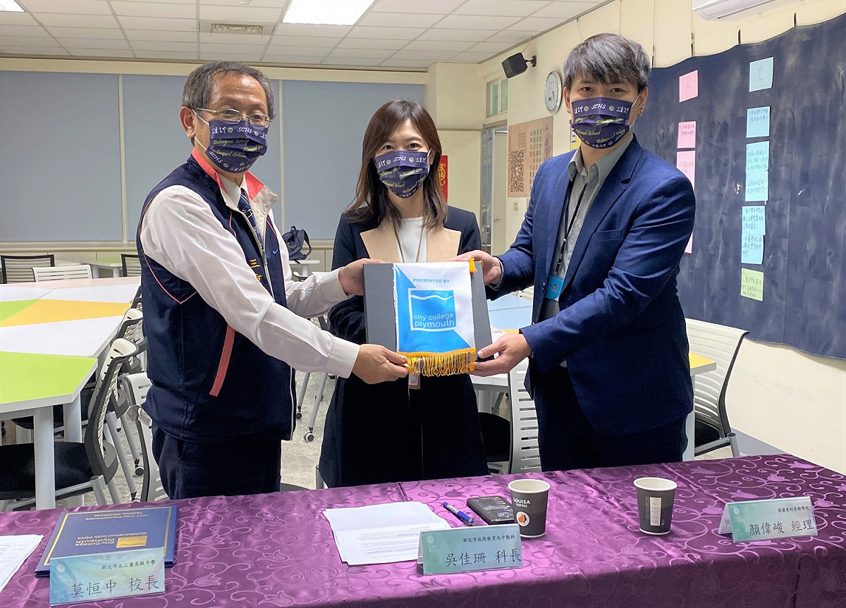 普利茅斯城市學院駐台灣辦公室經理顏偉峻(右一)致贈三重高中校長莫恒中(左一)紀念品。 圖：新北市教育局提供