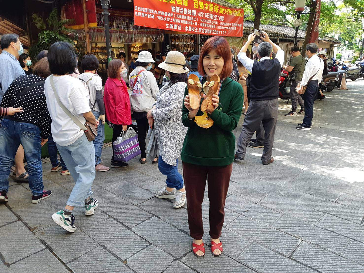 嘉義市木屐女王為感恩躲過火劫，每雙木屐只需樂捐1元，民眾拿到木屐後非常開心。 圖：蔡坤龍/攝