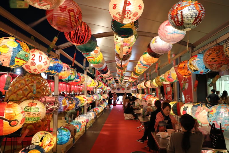 2022東京鐵塔台灣祭活動遊客一入會場可看到來自台南府城普濟燈會布置的彩繪燈籠所搭建的隧道。由於日本人放黃金週長假，生意超好，餐桌擺在花燈隧道內。 圖/中央社