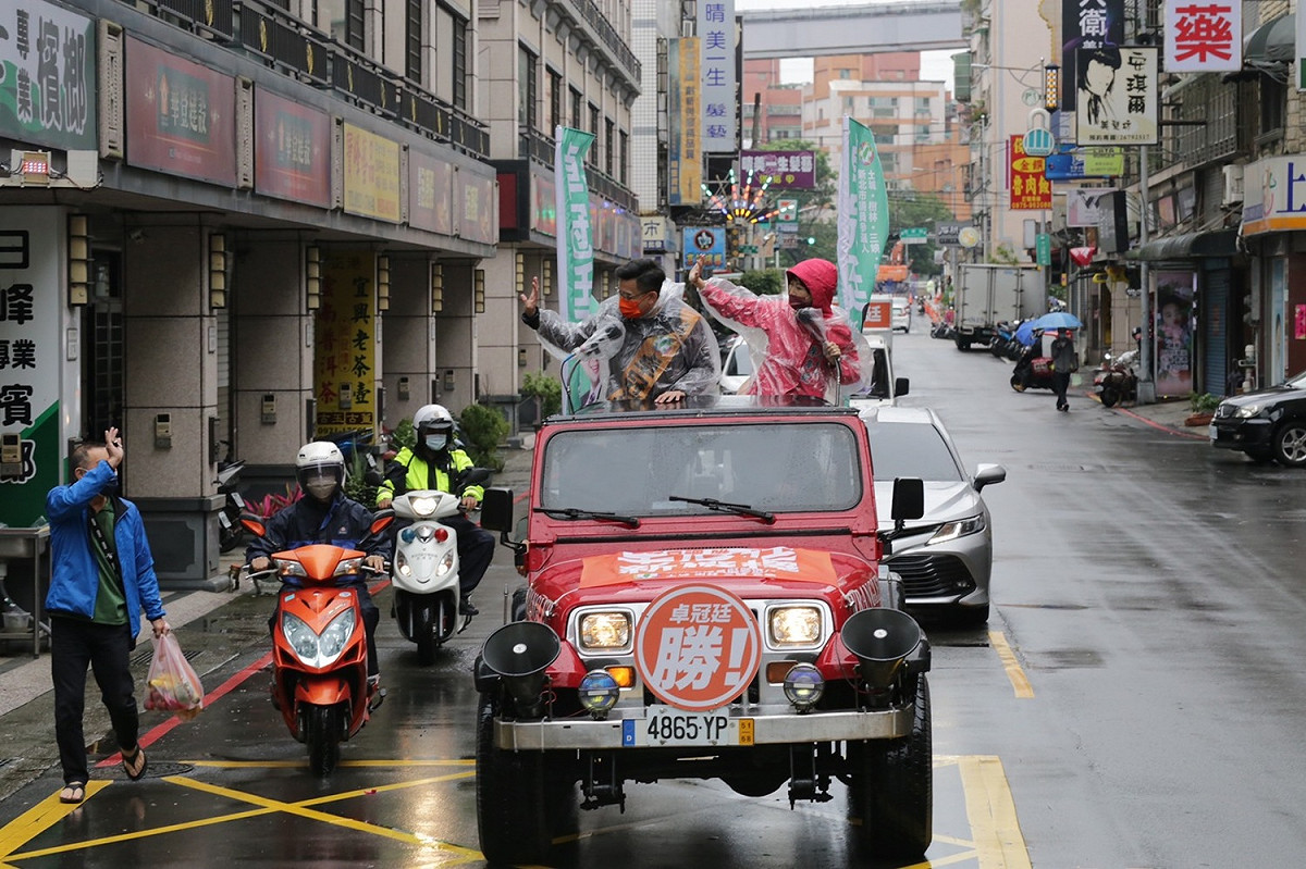卓陳站上吉普車，在雨中開始車隊掃街。雖然雨勢越來越大，不過兩人稱風雨不狼狽，要堅定接受民意洗禮。 圖：卓冠廷辦公室提供