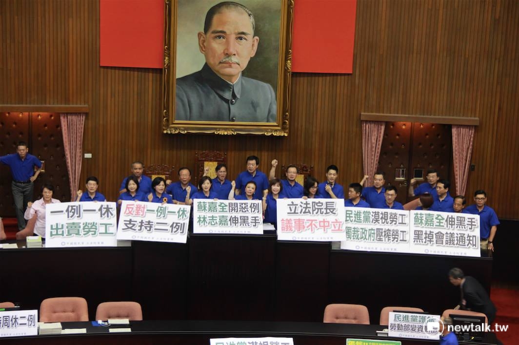 立法院1日舉行院會，國民黨立委穿著藍色戰服，一湧而上占領主席台，並舉著「反對一例一休、支持二例」 等看板。 圖：鄭佑漢/攝