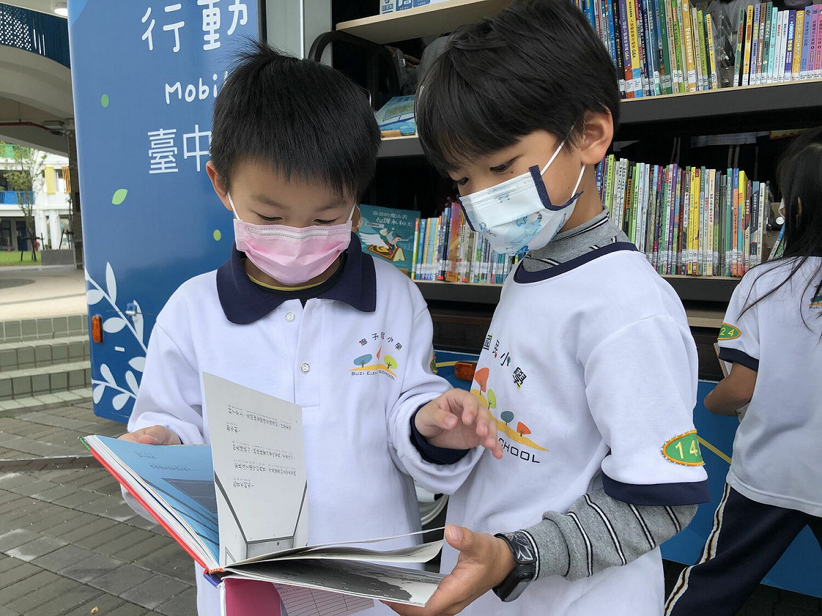 學童在書車前開心翻閱圖書。 台中市政府/提供