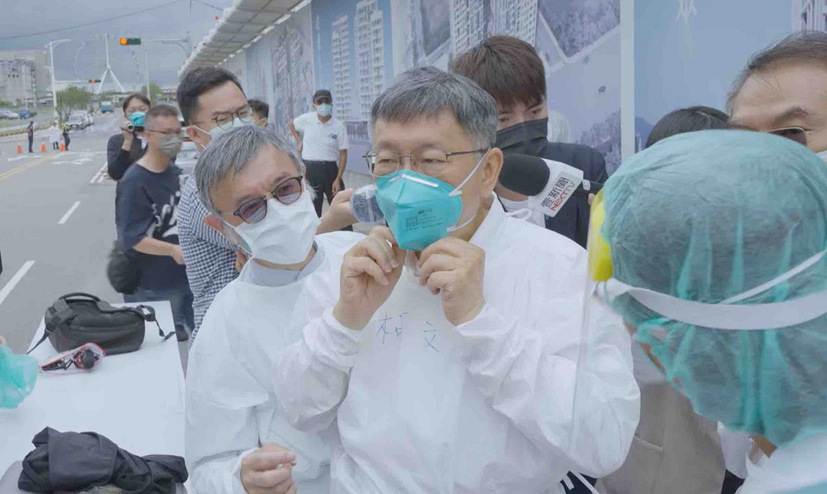 柯文哲視察車來速採檢站時，包含視一同察的官員與醫療團隊，幾乎全員穿著防護衣與N95口罩。 圖：翻攝自柯文哲臉書