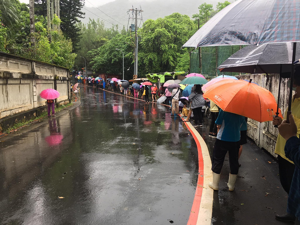 許多民眾為了領取松山慈惠堂免費發放的快篩劑，冒雨排隊。 圖：網友授權提供