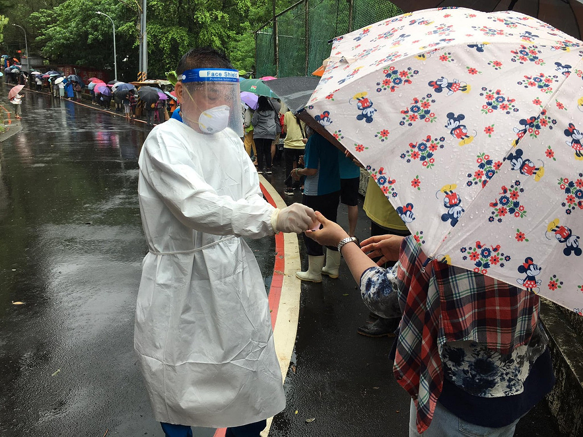許多民眾為了領取松山慈惠堂免費發放的快篩劑，冒雨排隊。 圖：網友授權提供