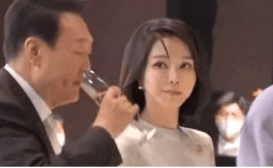 南韓總統尹錫悅正端著酒杯準備喝酒，一旁的總統夫人金建希立即轉頭，用十分銳利的眼神盯著尹錫悅。 圖 : 影片截圖