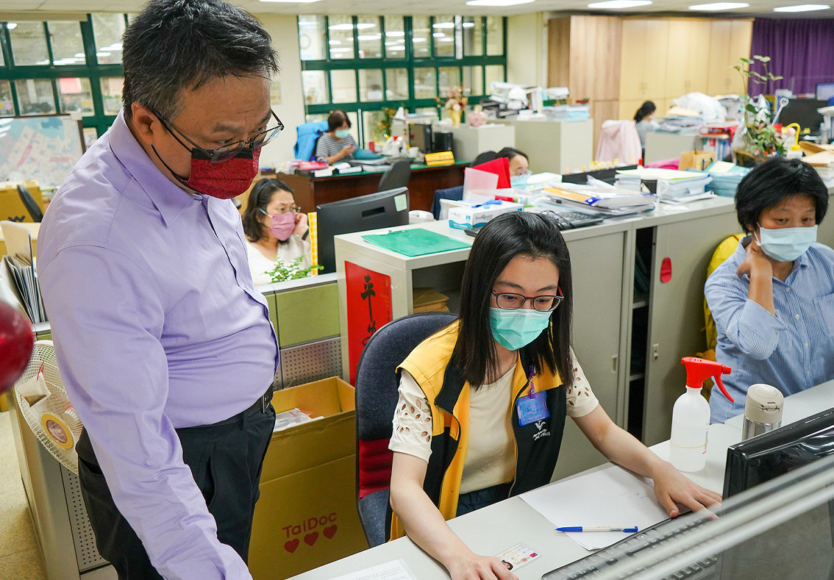 主任秘書柯建輝（左）與林口戶政事務所支援同仁（中）協助現場民眾領取快篩劑或關懷包。 圖：林口區公所提供