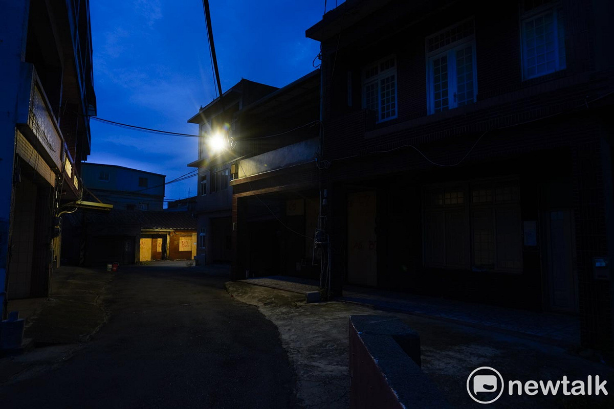 入夜後，巷弄內的住家陷入黑夜之中，用來封住老屋門窗的木板在街燈照射下，顯得明亮又詭譎。 圖：張良一/攝