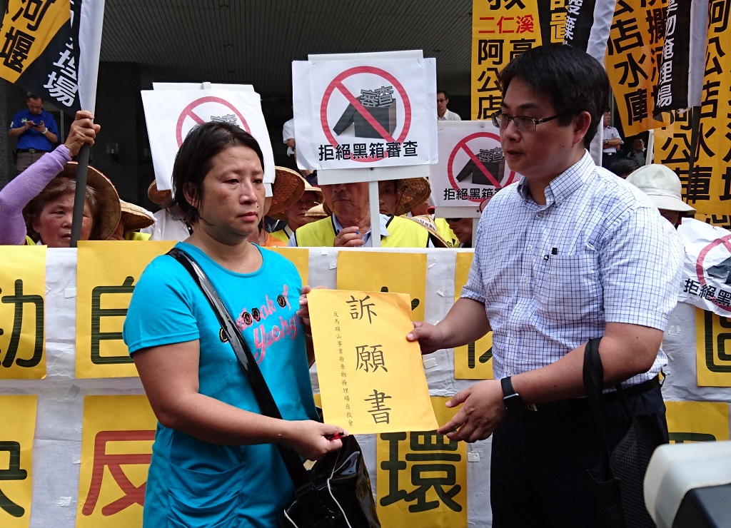 環保團體25日上午至高雄市政府前抗議，富駿事業廢棄物掩埋場現勘未通知當地居民，由環保局人員(右)接下訴願書。 圖：水資源保育聯盟提供