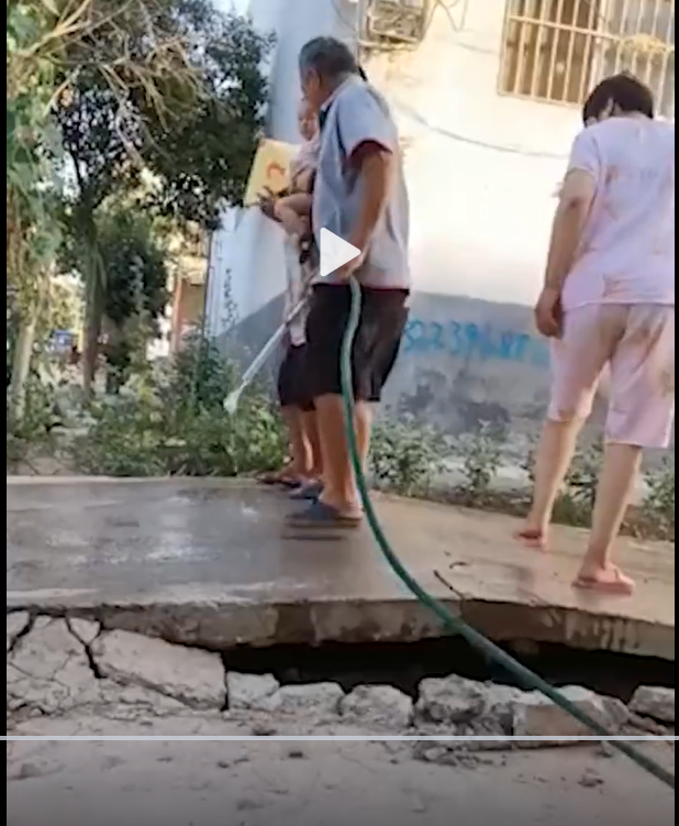 河南一處水泥路面因高溫膨脹，附近居民試圖灑水降溫。 圖:翻攝自微博