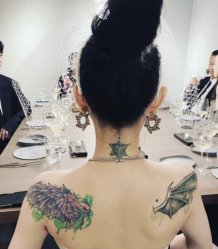 大S露出嫩白美背與刺青，背景中可見陳建州夫婦身影。 圖：翻攝自 happyyali IG