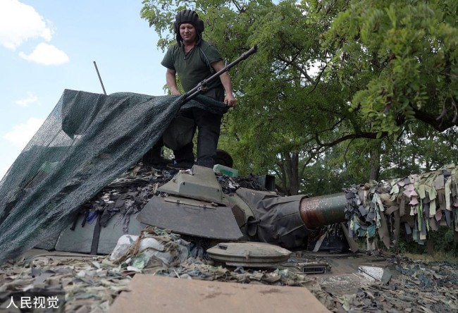 頓巴斯地區，烏克蘭軍人蓋住一輛坦克作為掩護。 圖:翻攝自視覺中國