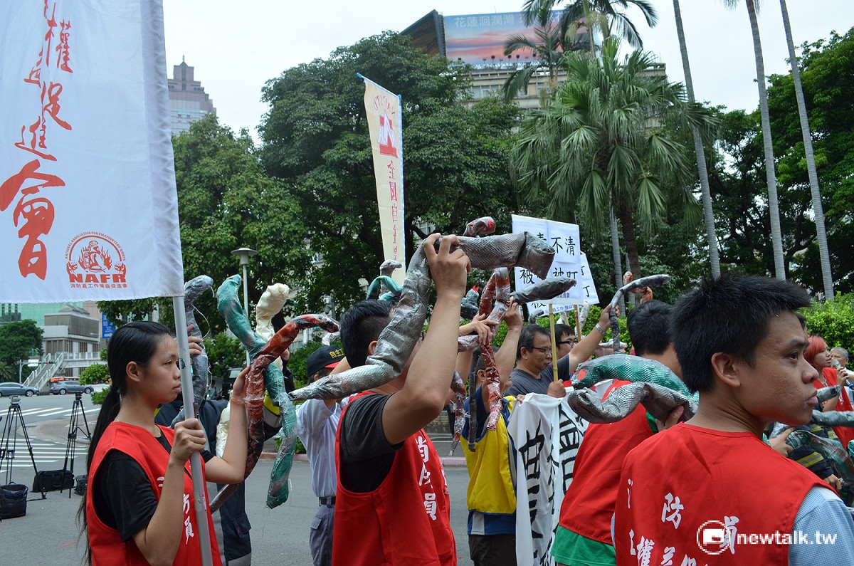 消防員將道具蛇丟向行政院，象徵「將蛇還給政府」。 圖：柯昱安/攝