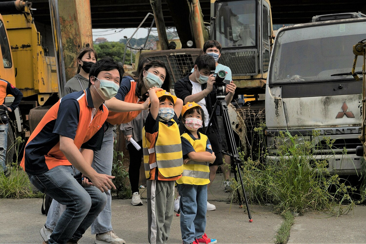 小小清潔隊員專注地看清潔隊員示範從高高的電線桿上撕下小廣告。