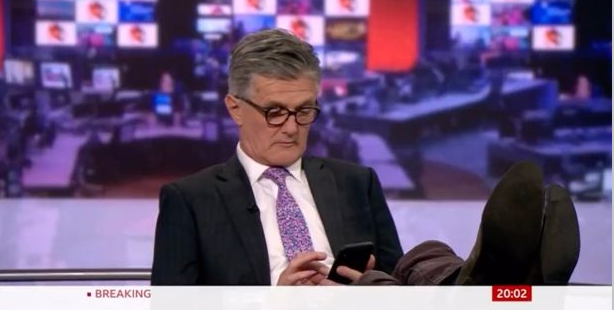 BBC新聞主播蒂姆·威爾考克斯( Timothy Melton Willcox )被拍到在主播台翹腳、低頭滑手機。 圖 : 翻攝自推特