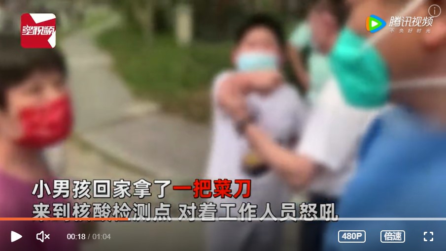 中國一名男孩(圖中)不滿被核酸檢測工作人員管教，持刀向工作人員怒吼。 圖：翻攝自騰訊